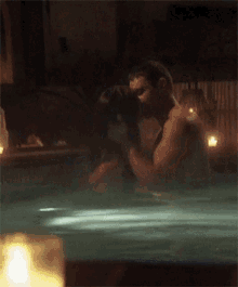 a man and woman kissing in a hot tub with candles in the background