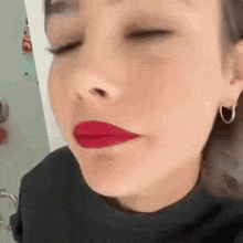a close up of a woman wearing red lipstick and earrings .