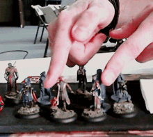 a person 's finger is pointing at a group of figurines with the letter b on the bottom