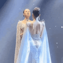 a woman in a white dress with a blue cape