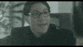 a black and white photo of a woman wearing glasses and a black shirt