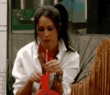 a woman in a white shirt is smoking a red bong
