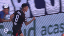 a soccer player wearing a number 8 jersey is running on the field