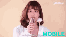 a woman is eating an ice cream cone in front of a mobile logo .