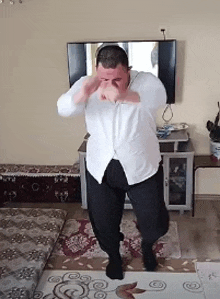 a man is dancing in a living room in front of a tv .