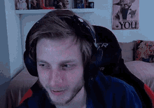 a man wearing headphones is sitting in a chair in front of a poster that says you