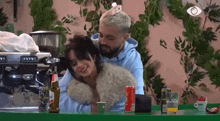 a man and a woman are sitting at a table with a can of soda on it .