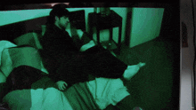 a tv screen shows a man laying on a bed with a green background