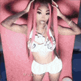 a woman with pink hair is wearing a white top and shorts .