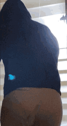 a person wearing a black hoodie is standing in front of a window with blinds