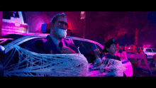 a man is wrapped in a spider web while sitting in a car .