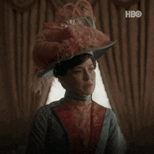 a woman wearing a feathered hat says " what can i do " in white letters