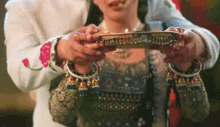 a man and a woman are holding a tray in their hands . the woman is wearing a necklace and earrings .