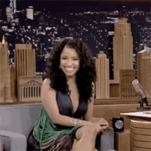 a woman is sitting on a couch smiling in front of a city skyline