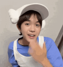 a young boy wearing a white hat and a blue shirt is making a funny face