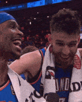 two basketball players are laughing and one has a towel around his neck that says thunder