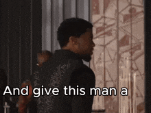 a man standing in front of a wall with the words " and give this man a "