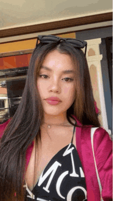 a woman with long hair wearing sunglasses and a pink jacket
