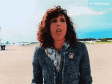 a woman is standing on a runway with planes in the background and the name dr pflaumisan is on the bottom