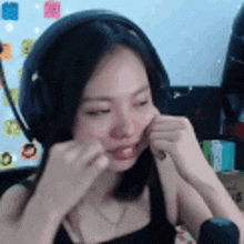 a woman wearing headphones and a black tank top is making a funny face .