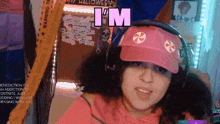 a woman wearing headphones and a pink hat says " i 'm "