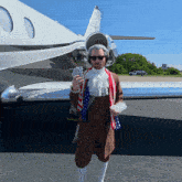 a man dressed as abraham lincoln stands in front of an airplane holding a stack of money