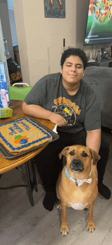 a man and a dog are sitting at a table with a birthday cake on it