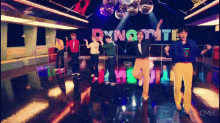 a group of people are dancing in front of the word dynamite