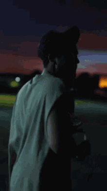 a man in a sleeveless shirt is walking down a street at night