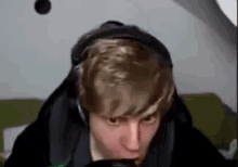 a man wearing headphones and a hoodie is looking at the camera .