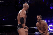 a referee is standing in the middle of a wrestling ring watching two men fight .