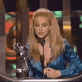 a woman in a blue dress is giving a speech in front of a microphone .