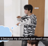 a man in a camo shirt stands in front of a men 's restroom