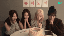 a group of girls praying in front of a cake with chinese writing on the wall