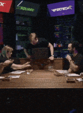 a group of people are sitting around a table with a vipertech sign in the background