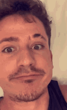 a man with a beard is making a funny face with his eyes wide open