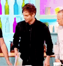 a man in a black shirt is standing in a kitchen