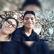 a man and a woman are posing for a picture together . the woman is wearing glasses .