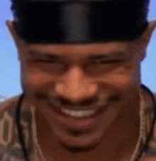 a man wearing a black hat and a necklace is smiling and making a funny face .