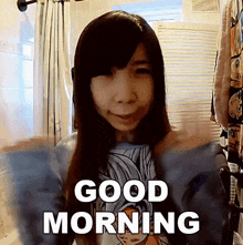 a woman in a blue shirt says good morning with her arms outstretched
