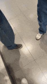 a person standing on a tiled floor wearing a pair of white shoes