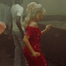a woman in a red dress is dancing with a man behind her