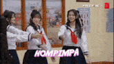 three girls in school uniforms are dancing with the word hompimpa written in pink