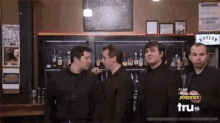 a group of men are standing in front of a bar with a sign that says jokers on it .
