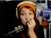a woman wearing headphones and a headband is biting her nails in front of a microphone