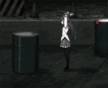 a girl is standing next to a black barrel with a red ball on it