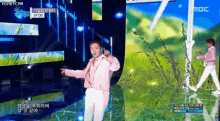 a man in a pink jacket is dancing on a stage in front of a mbc logo