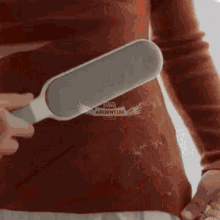 a person is using a brush to remove lint from a red sweater