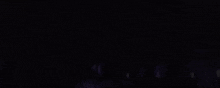 a purple and white glowing object is moving in the dark on a black background .