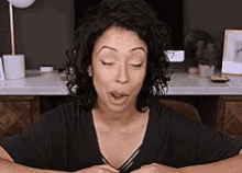 a woman is making a funny face while sitting at a desk with her eyes closed .